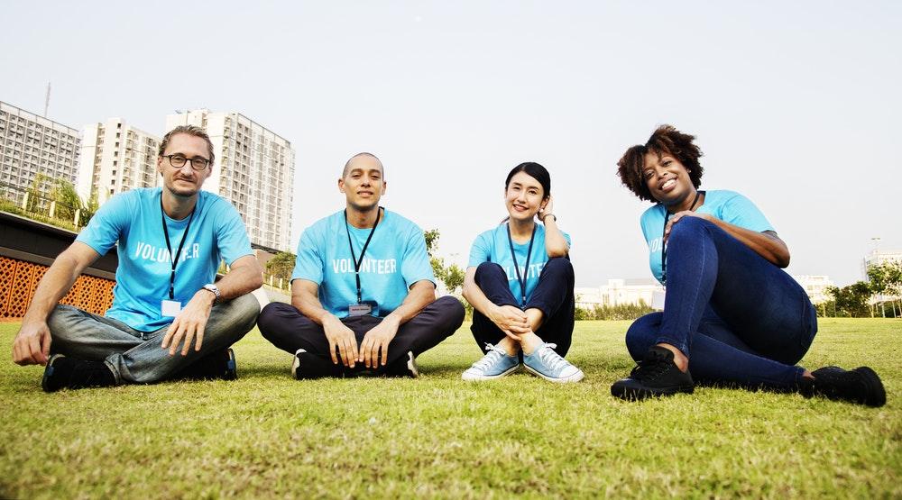 two men and two women sitting on green grass field during daytime