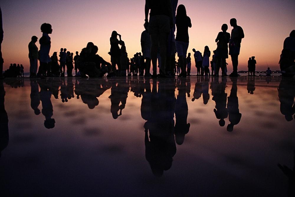 silhouette of people standing on mirror during golden hour