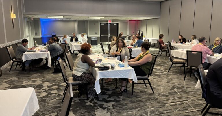 Participants working in small groups at round tables during a workshop